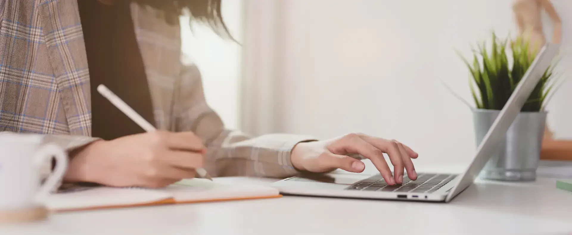 Woman typing on her computer and making notes